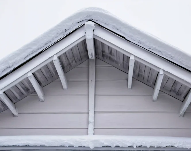 close up of a snowy wooden roof with white siding free photo